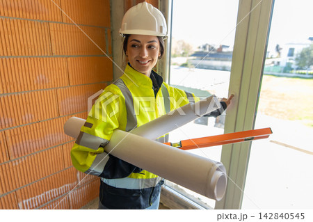 Happy female architect holding rolled blueprints Happy female architect holding rolled blueprints 142840545