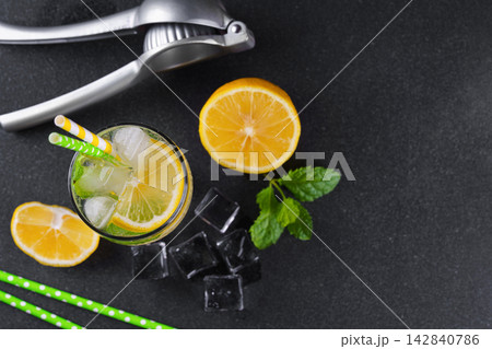 Refreshing homemade lemonade with lemon slices, fresh mint, ice and citrus juicer, cold beverage 142840786
