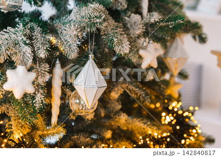 Christmas tree branch decorated with white ornaments, star, icicles and glowing lights, holiday mood 142840817