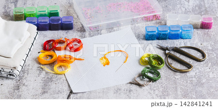 Cross-stitch, Aida cloth, colorful embroidery floss, and scissors on the table web banner Cross-stitch, Aida cloth, colorful embroidery floss, and scissors on the table web banner 142841241