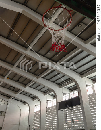 A striking vertical view capturing the intersection of mid-century architecture and sports culture. The red-and-white woven net takes center stage beneath the dramatic curve of massive white concrete A striking vertical view capturing the intersection of mid-century architecture and sports culture. The red-and-white woven net takes center stage beneath the dramatic curve of massive white concrete 142841387