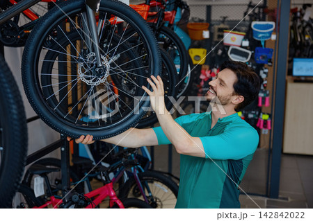 Mechanic fixing wheel amidst vibrant bikes Mechanic fixing wheel amidst vibrant bikes 142842022