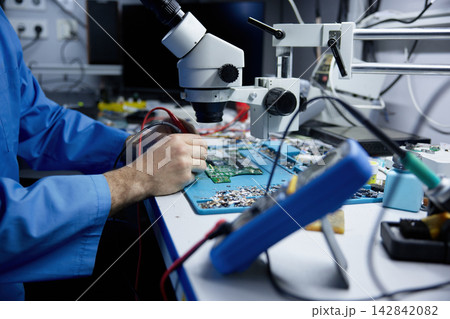 Man is repairing on electronic repair workbench equipped with circuit board 142842082