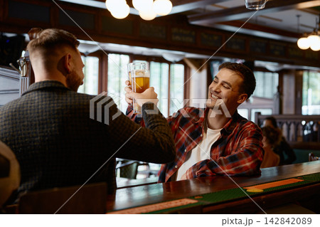 Two caucasian men share relaxed moments and cheerful conversations at friendly pub 142842089