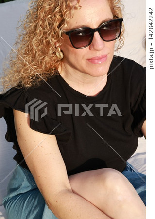 Smiling Woman Enjoying a Sunny Summer Day by the Pool 142842242