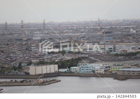 海岸沿いの工場地帯と高速道路橋と川と市街地の街並みと空の風景 海岸沿いの工場地帯と高速道路橋と川と市街地の街並みと空の風景 142844503