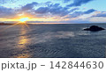 朝焼けの海と雲間から差し込む朝日（日の出の光条と小島） 142844630
