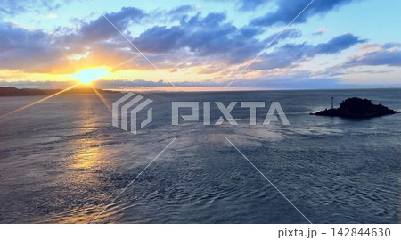 朝焼けの海と雲間から差し込む朝日(日の出の光条と小島) 朝焼けの海と雲間から差し込む朝日(日の出の光条と小島) 142844630