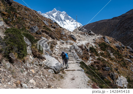 Rear view of tourist trekking in Sagarmatha national park, Nepal with beautiful view of Mt.lhotse (8,516 m) in the background. Rear view of tourist trekking in Sagarmatha national park, Nepal with beautiful view of Mt.lhotse (8,516 m) in the background. 142845418