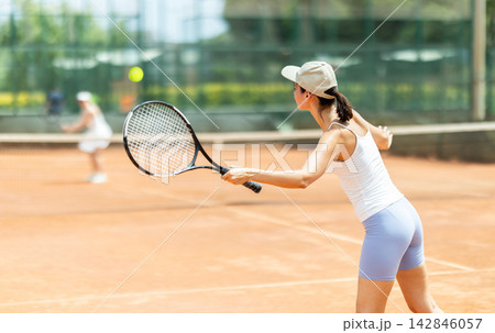 Female athlete plays tennis on open court 142846057