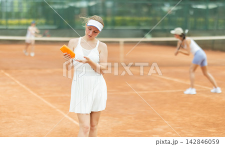 On tennis court, girl applies sunscreen to body 142846059