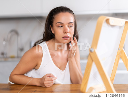 Young woman looking at mirror in kitchen Young woman looking at mirror in kitchen 142846166