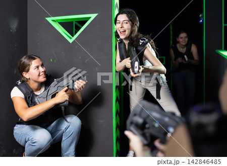 Girls play laser tag, jokingly fight with light weapons Girls play laser tag, jokingly fight with light weapons 142846485