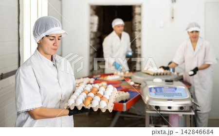 Hispanic female worker of poultry farm holding cardboard tray with eggs 142846684