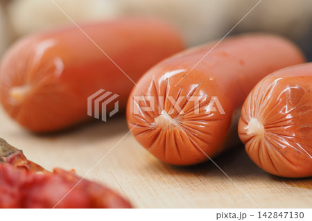 Preparation of fresh sausages on a wooden table next to spices Preparation of fresh sausages on a wooden table next to spices 142847130
