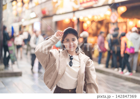 Happy woman traveler travel in Chengdu city. Tourist sightseeing and shopping in Jinli Ancient Street. Famous Landmark for tourism attraction in Sichuan, China Happy woman traveler travel in Chengdu city. Tourist sightseeing and shopping in Jinli Ancient Street. Famous Landmark for tourism attraction in Sichuan, China 142847369