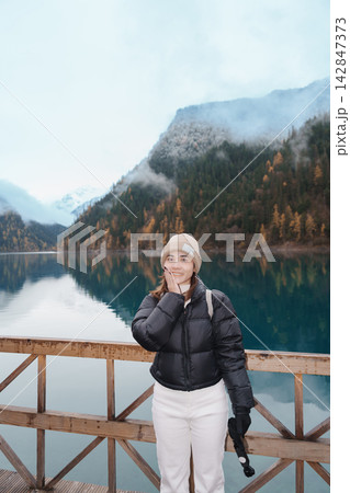 Happy woman traveler travel in jiuzhaigou national park in Sichuan, China. Tourist sightseeing Long lake and snow mountain in Autumn season. Famous Landmark and Vacation near Chengdu, China 142847373