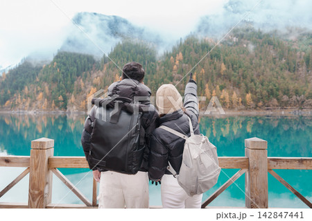 Happy Couple traveler travel in jiuzhaigou national park in Sichuan, China. Tourist sightseeing beautiful  lake and snow mountain in Autumn season. Famous Landmark and Vacation near Chengdu, China 142847441