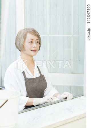 リビングで拭き掃除をするシニア女性 リビングで拭き掃除をするシニア女性 142847590
