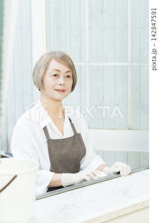 リビングで拭き掃除をするシニア女性 リビングで拭き掃除をするシニア女性 142847591