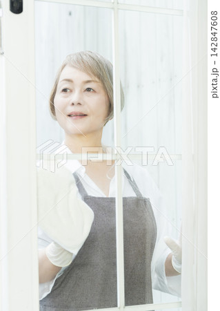 リビングで拭き掃除をするシニア女性 リビングで拭き掃除をするシニア女性 142847608