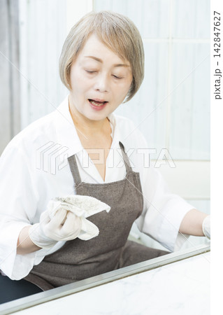 リビングで拭き掃除をするシニア女性 リビングで拭き掃除をするシニア女性 142847627