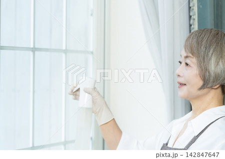 リビングで拭き掃除をするシニア女性 リビングで拭き掃除をするシニア女性 142847647