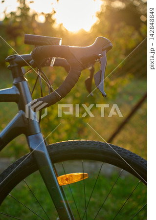 Close-up of a gravel bike with front wheel, drop handlebars at sunset 142848849