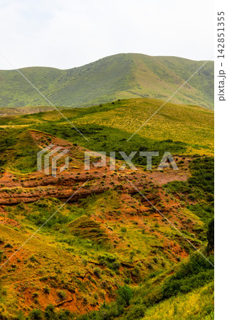 Rolling Green Hills and Eroded Red Earth Landscape in Kyrgyzstan Rolling Green Hills and Eroded Red Earth Landscape in Kyrgyzstan 142851355