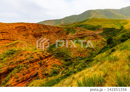 Dramatic Eroded Rock Formations and Green Hills in Kyrgyzstan Dramatic Eroded Rock Formations and Green Hills in Kyrgyzstan 142851356