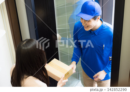 玄関で荷物を渡す配達員 玄関で荷物を渡す配達員 142852290