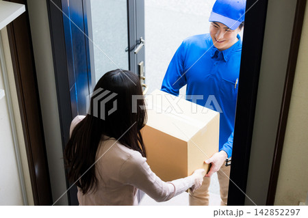 玄関で荷物を渡す配達員　  142852297