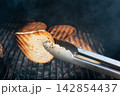 Grilled bread slices over hot coals with tongs. Rustic BBQ background Grilled bread slices over hot coals with tongs. Rustic BBQ background 142854437