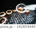 Grilled mushrooms over hot coals with tongs Grilled mushrooms over hot coals with tongs 142854440