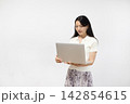 白い壁の前でノートパソコンを操作する若い日本人女性 142854615