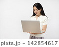 白い壁の前でノートパソコンを操作する若い日本人女性 142854617