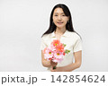 白い壁の前で花束を持ってカメラ目線で微笑む若い日本人女性 142854624