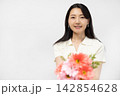 白い壁の前で花束を持ってカメラ目線で微笑む若い日本人女性 142854628