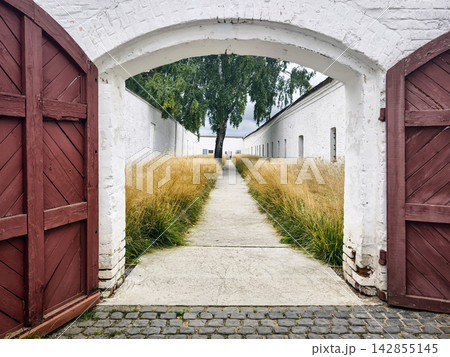 Walkway through an archway leading to a grassy path at a historic site Walkway through an archway leading to a grassy path at a historic site 142855145