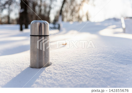 Stainless steel thermos in snowy winter landscape 142855676