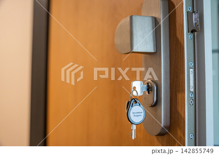 House keys with Investment Property keychain inserted into modern apartment door lock. Real estate investment and property ownership concept for passive income and wealth building 142855749