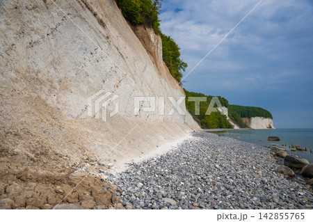 Famous white chalk cliffs and rocky Baltic Sea coastline in Jasmund National Park on Rugen island, Germany. Iconic natural landmark and coastal travel destination concept. Famous white chalk cliffs and rocky Baltic Sea coastline in Jasmund National Park on Rugen island, Germany. Iconic natural landmark and coastal travel destination concept. 142855765