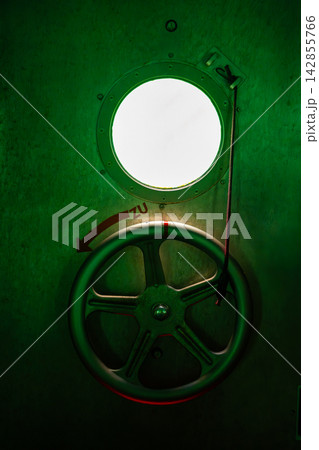 Metal hatch wheel and porthole inside the diving gondola at Sellin Pier on Rugen island, Germany. Nautical engineering and underwater technology concept. Metal hatch wheel and porthole inside the diving gondola at Sellin Pier on Rugen island, Germany. Nautical engineering and underwater technology concept. 142855766