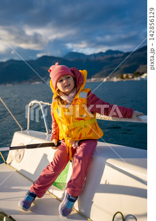 Little girl learning to sail a yacht during training in the Kotor Bay, Montenegro, representing adventure, freedom, and nautical sport. 142856129