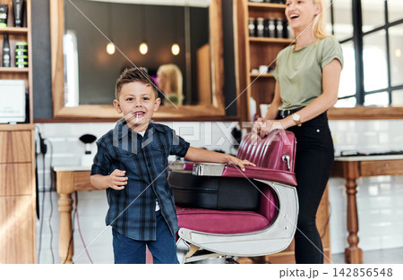 Happy, hairdresser and portrait of child in barbershop for hair care, grooming and beauty. Professional, service and kid smile with pride in salon, store and appointment with woman for hairstyle Happy, hairdresser and portrait of child in barbershop for hair care, grooming and beauty. Professional, service and kid smile with pride in salon, store and appointment with woman for hairstyle 142856548