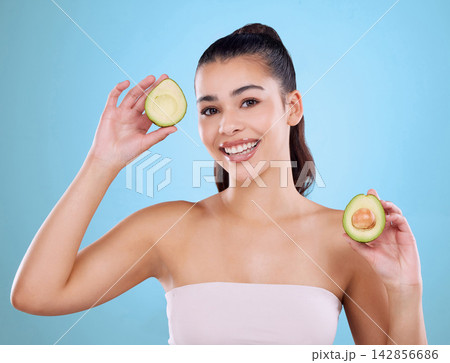 Girl, portrait and beauty in studio with avocado for healthy diet, skincare or anti aging for glowing skin. Model, hair health or happy with fruit for natural cosmetics or wellness on blue background 142856686