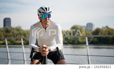 Male cyclist resting on road bike outdoors 142856821