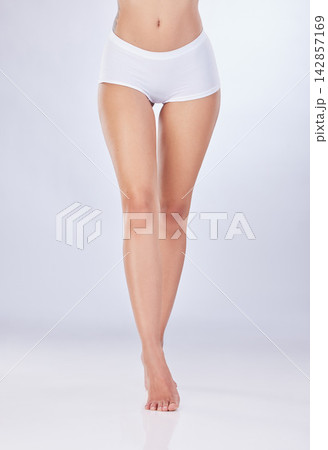Closeup, legs and woman with skincare, underwear and dermatology on white studio background. Person, model or human with beauty, aesthetic or cosmetics with shine, clear skin or glowing with wellness 142857169