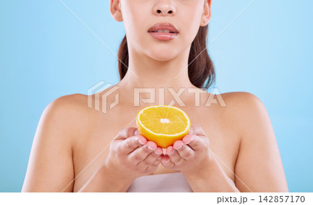 Woman, hands and orange for skincare in studio on white background and satisfied with routine. Natural, beauty and organic with confidence on portrait for skin treatment, ingredient and glow 142857170