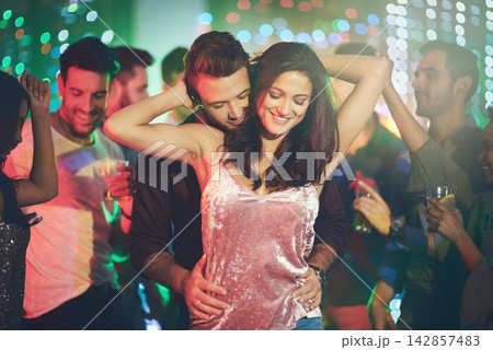 Couple, love and dance in club at night on date with romance in marriage or relationship. People, celebrate and embrace together with happiness at disco, party or rave at techno music with freedom 142857483
